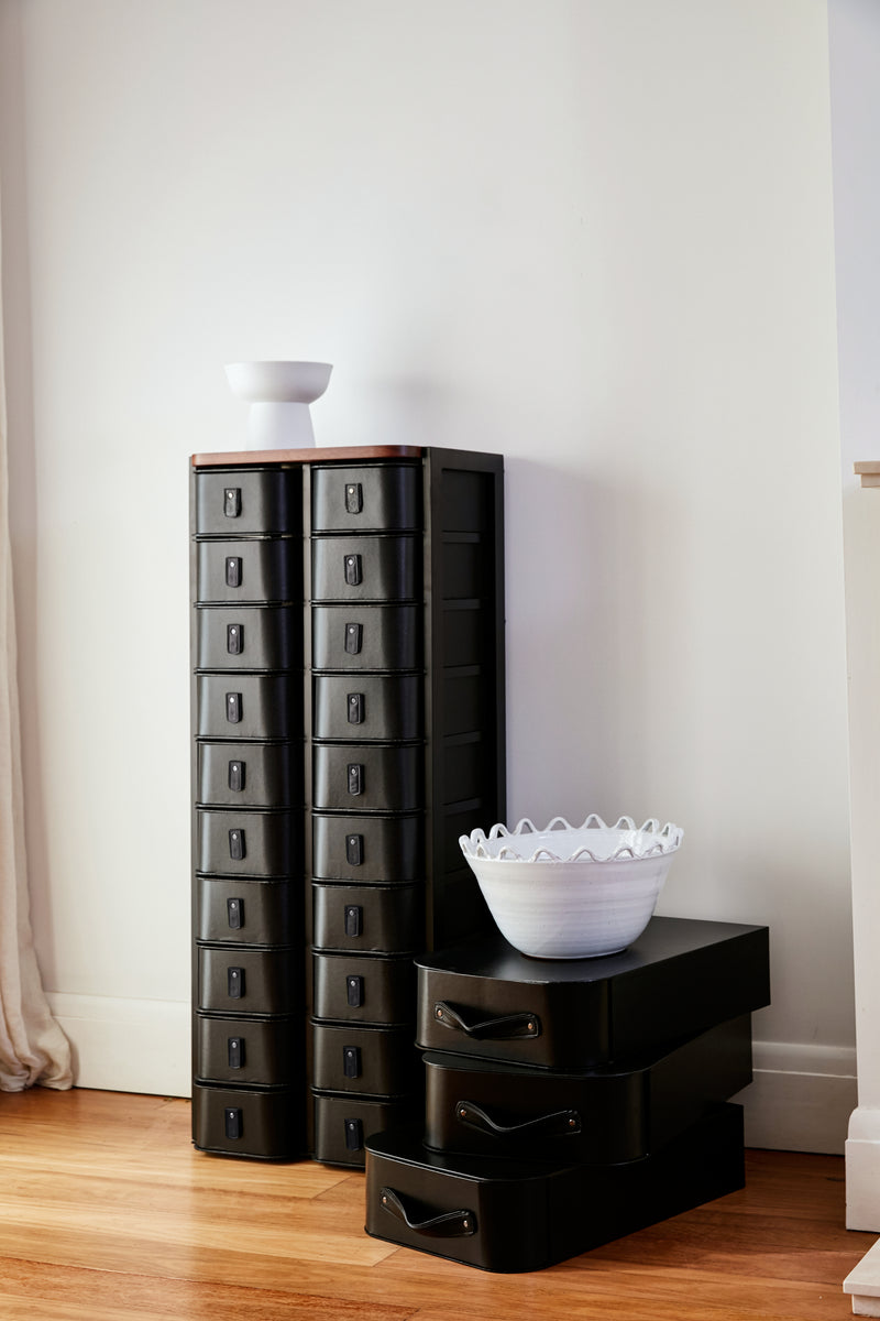 Black metal storage drawers with multiple compartments, styled in a modern, minimalist fashion.