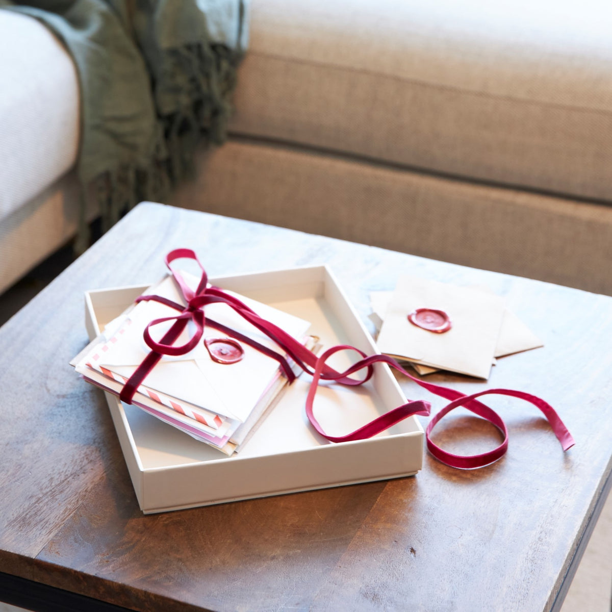 Gift box with red ribbon and wax seal, containing assorted stationery and decorative envelopes from SAGITINE.
